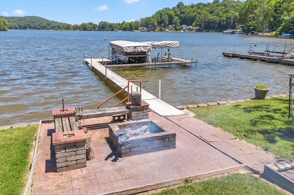 A dock with a boat lift and a stone fire pit on the Lake Lemon shoreline